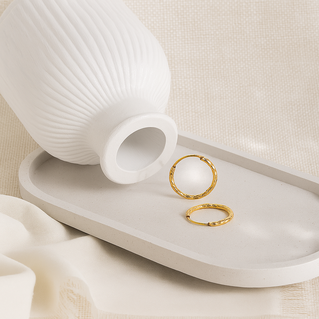 Two gold rings on a white surface with a white vase in the background