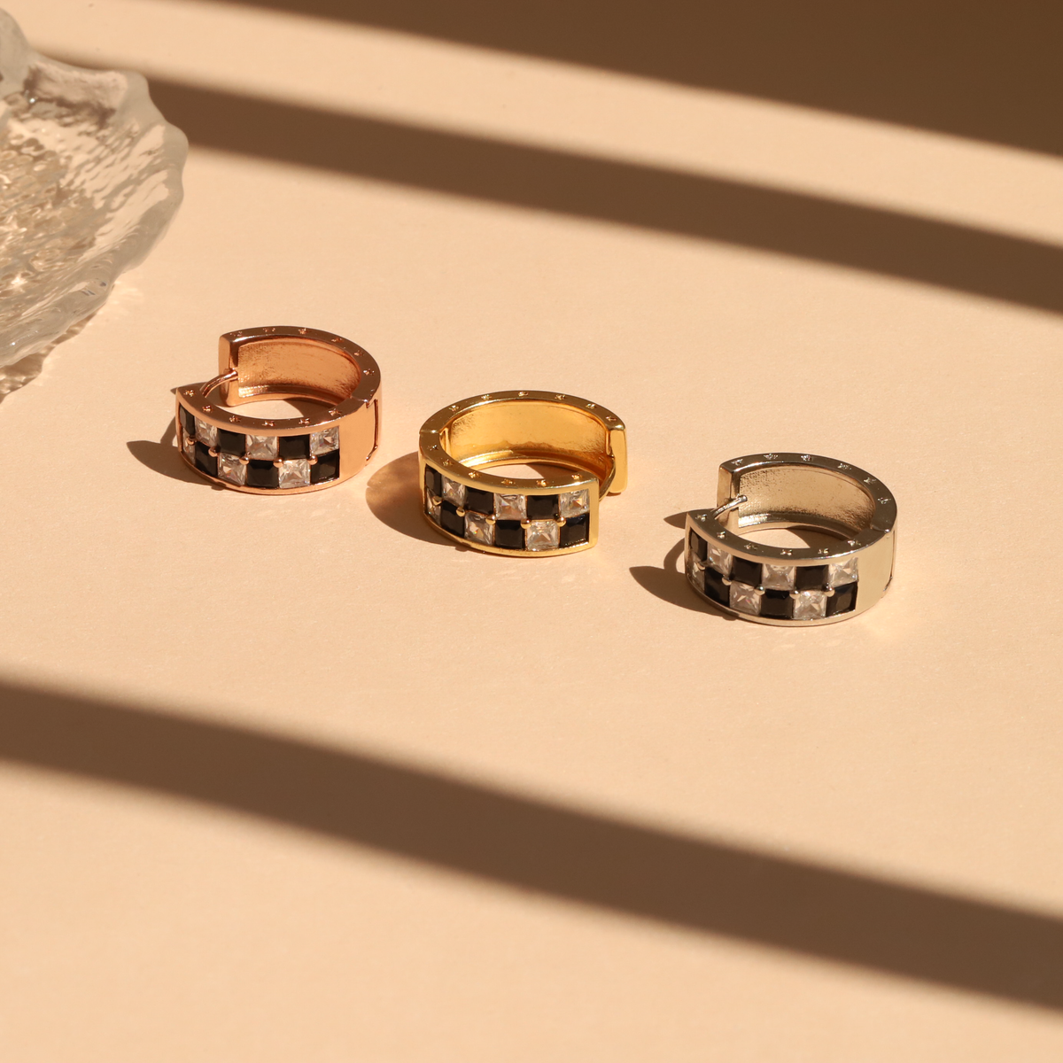 Three hoop earrings with a checkered pattern on a beige surface