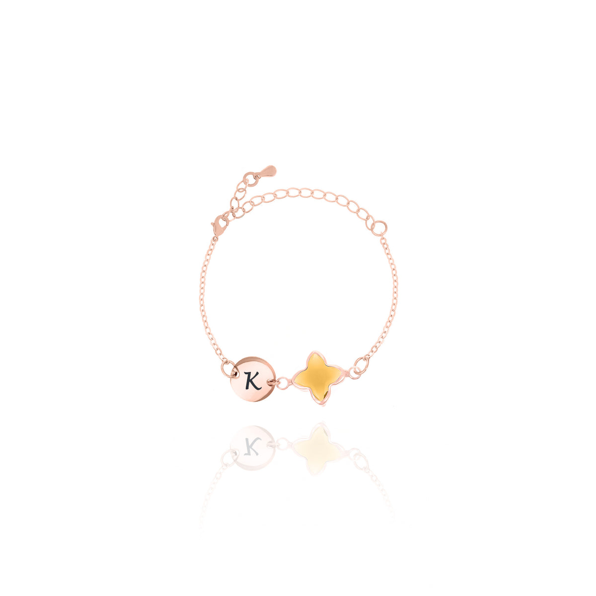 Rose-gold-tone bracelet with engraved K initial disc and amber four-lobed stone on white background