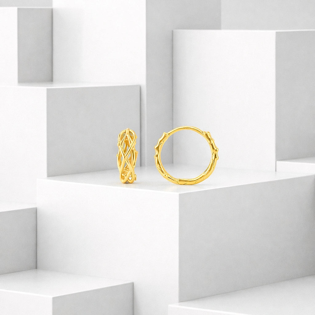 Pair of gold-tone huggie hoop earrings displayed on white geometric blocks