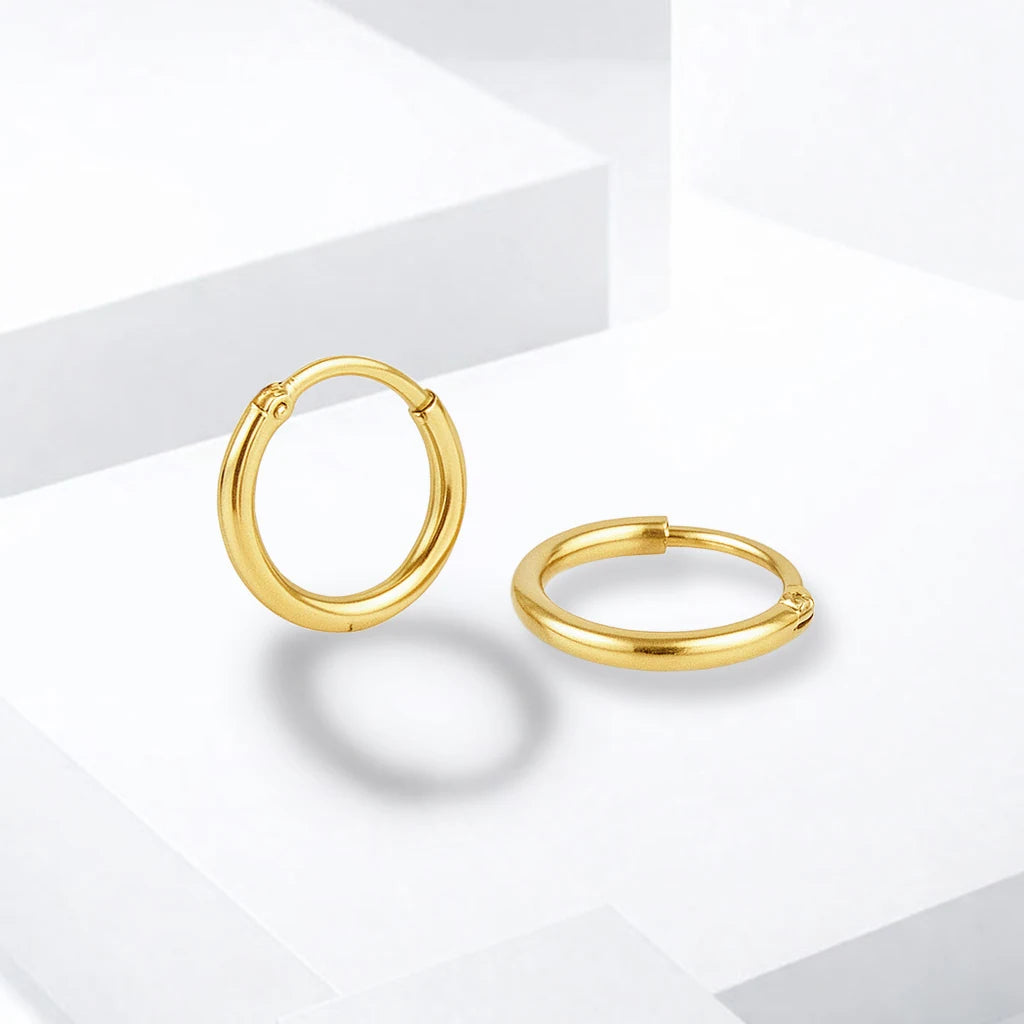 Gold-tone plain huggie hoop earrings displayed on white geometric blocks