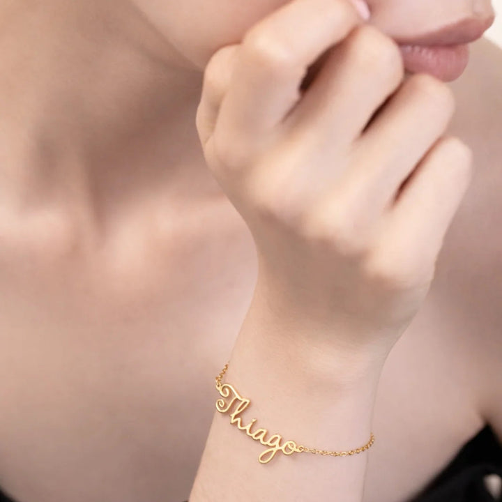 Gold bracelet with 'Thiago' on a wrist against a neutral background
